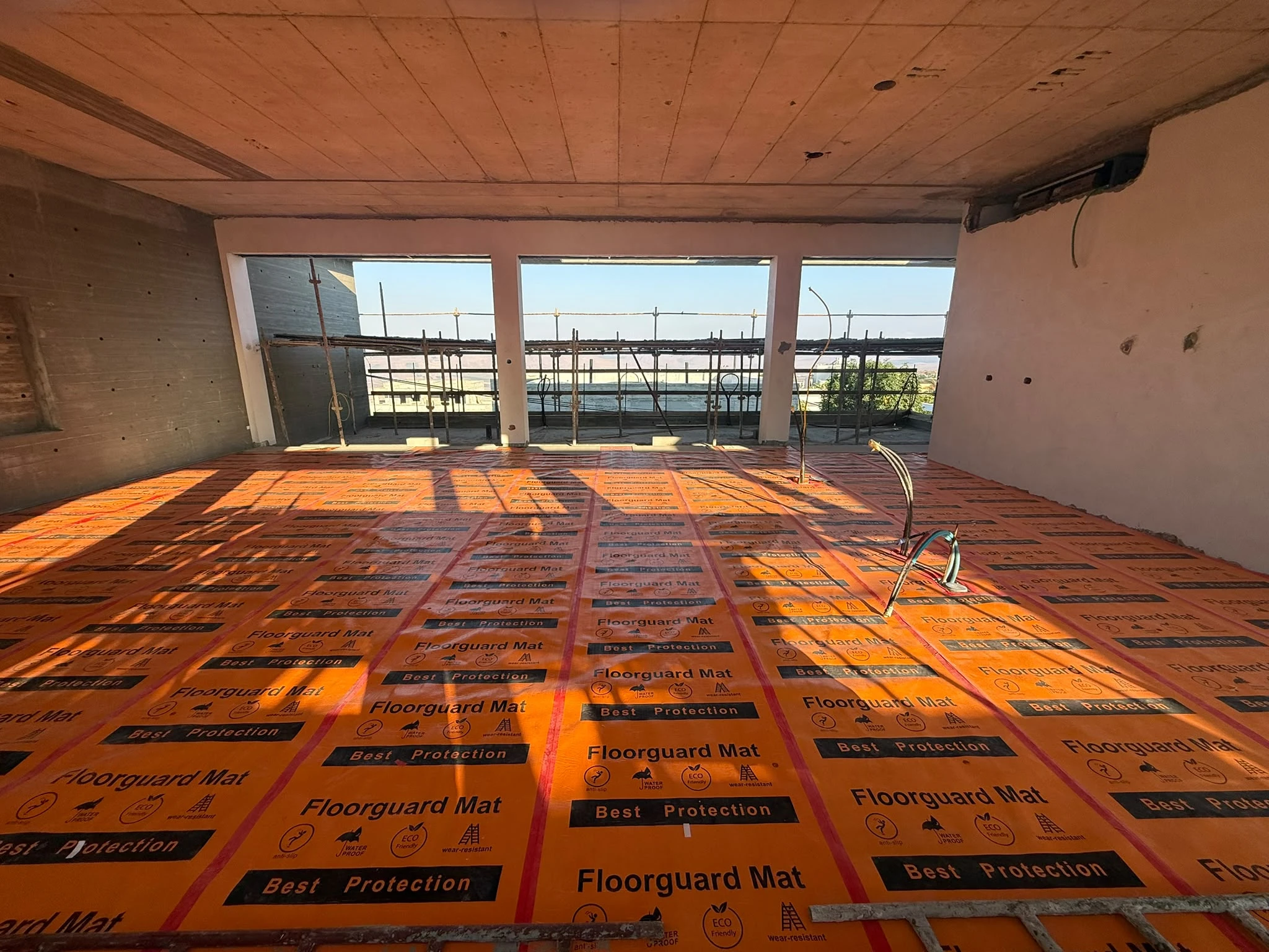 פועל פורש יריעת הגנה FloorGuard על רצפה לפני עבודות שיפוץ